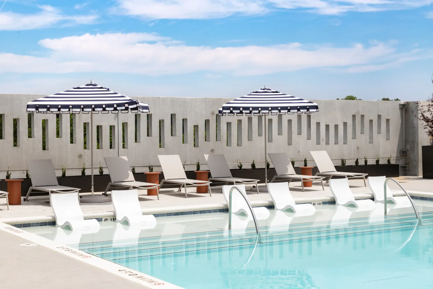 Rooftop swimming pool with in-water loungers and striped umbrellas at Everhill Kennesaw in Marietta